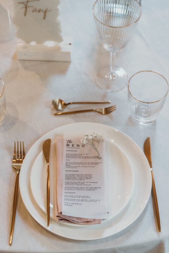Beautifully arranged table setting with gold cutlery and menus for a wedding reception.