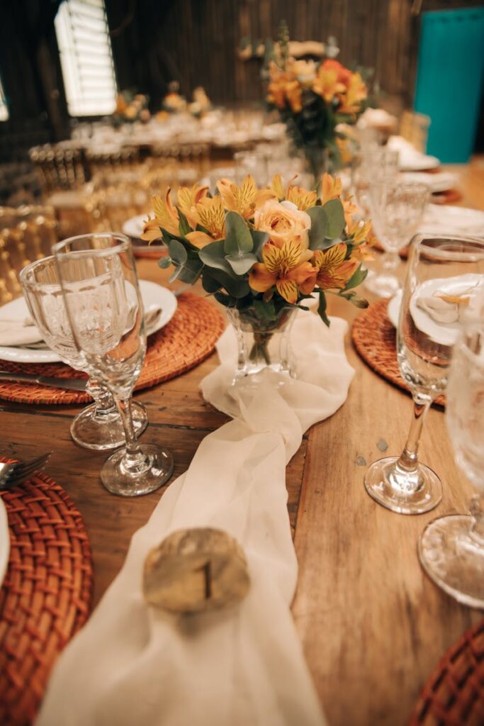 Cozy indoor dining table setup featuring flowers, plates, and wineglasses.