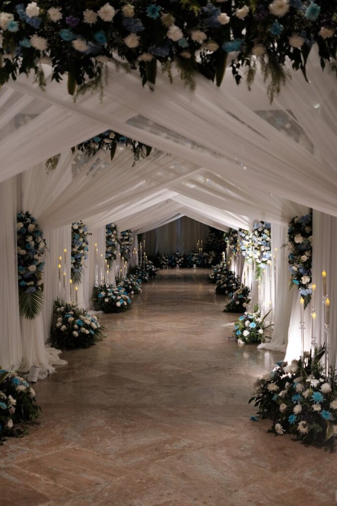 Luxurious wedding venue with white drapery and floral arrangements creating a sophisticated ambiance.