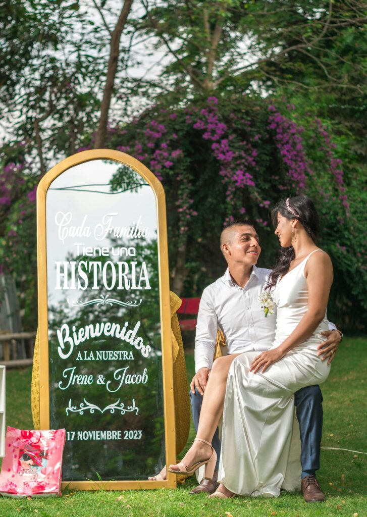 A couple in love sitting by a decorated mirror at their outdoor wedding in Ecuador.