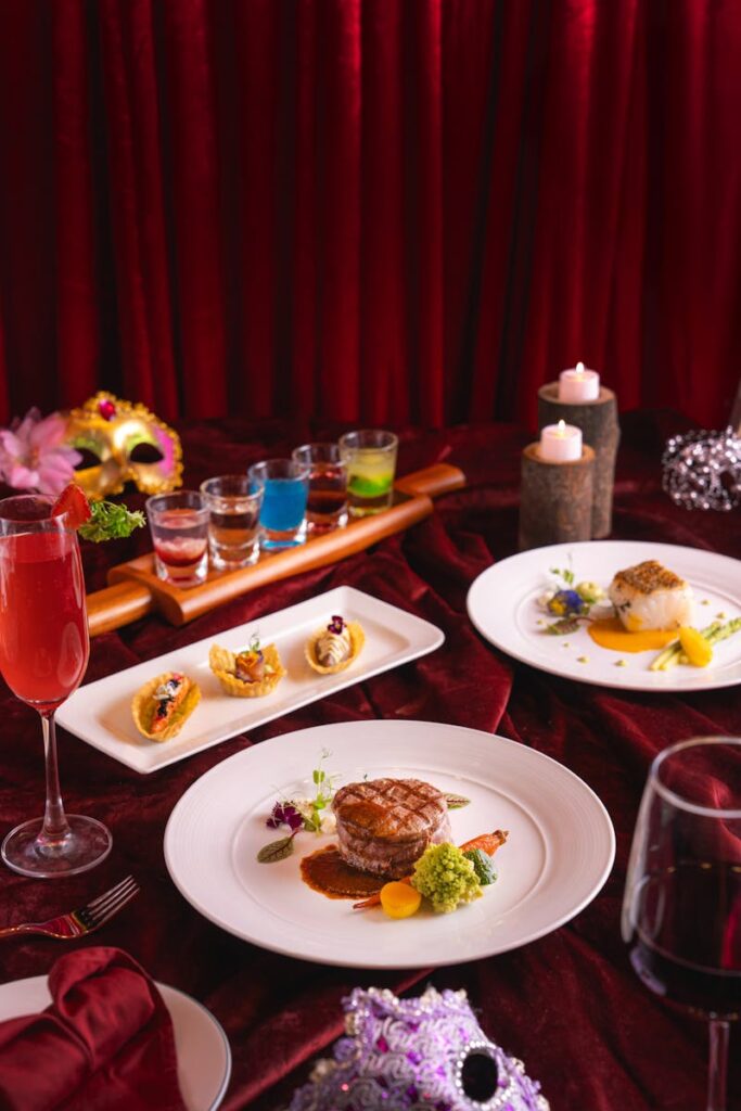 Luxurious gourmet dinner setting with red velvet background and artistic food presentation.