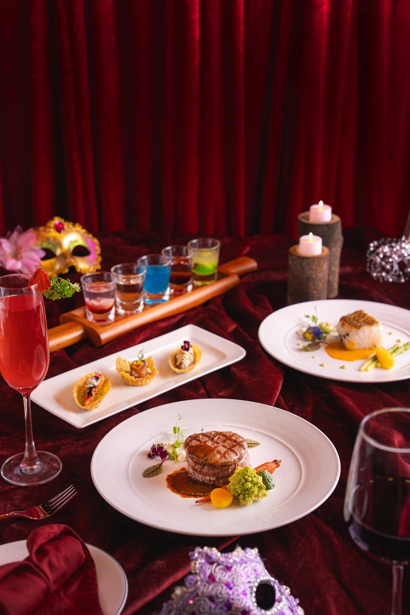 Luxurious gourmet dinner setting with red velvet background and artistic food presentation.