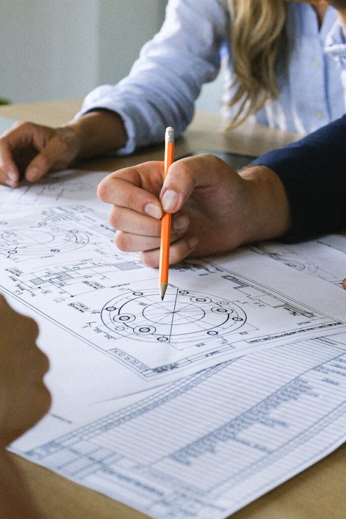 Group of crop anonymous colleagues gathering to discuss business project on papers at table